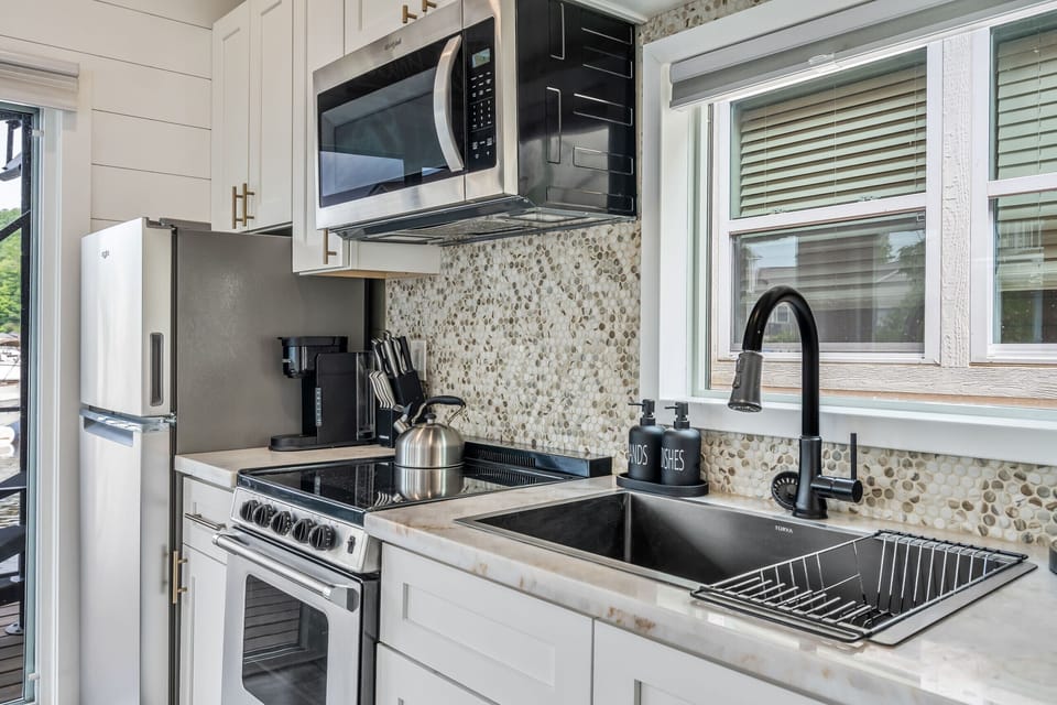Fully equipped kitchen with stainless appliances, a smooth-top range, microwave, coffee maker, and deep sink with sprayer faucet