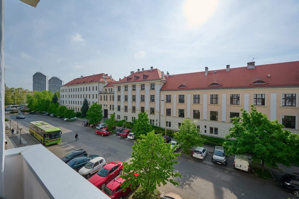 The view from the balcony showcases a peaceful residential area with well-maintained buildings and greenery.