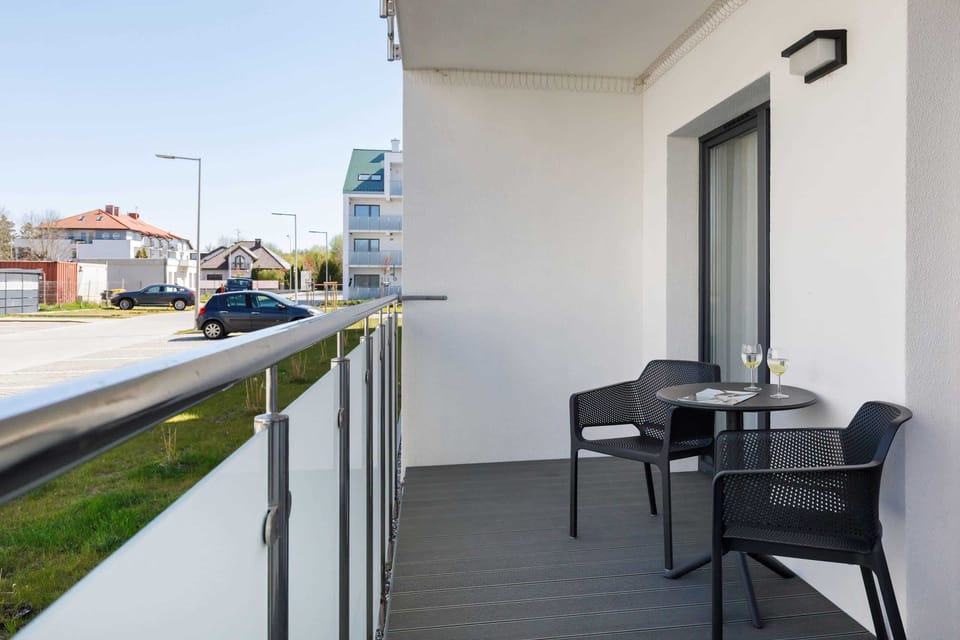 A private balcony featuring a small table and chairs, overlooking a peaceful garden.