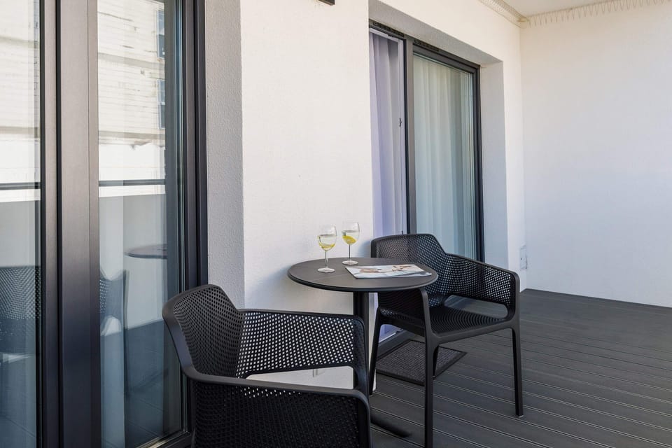 A private balcony featuring a small table and chairs, overlooking a peaceful garden.