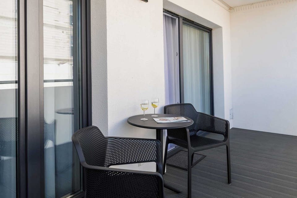 A private balcony featuring a small table and chairs, overlooking a peaceful garden.