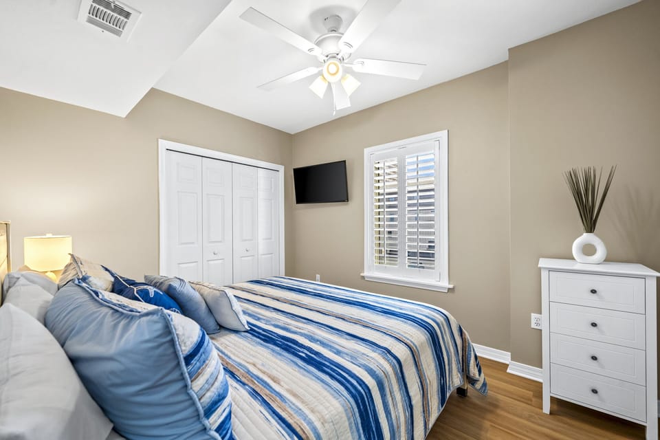 2nd bedroom with king bed, chest of drawers, wall mounted tv and closet