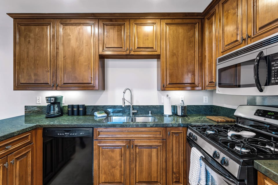 Fully equipped kitchen with double sink, gas range, and wood cabinetry