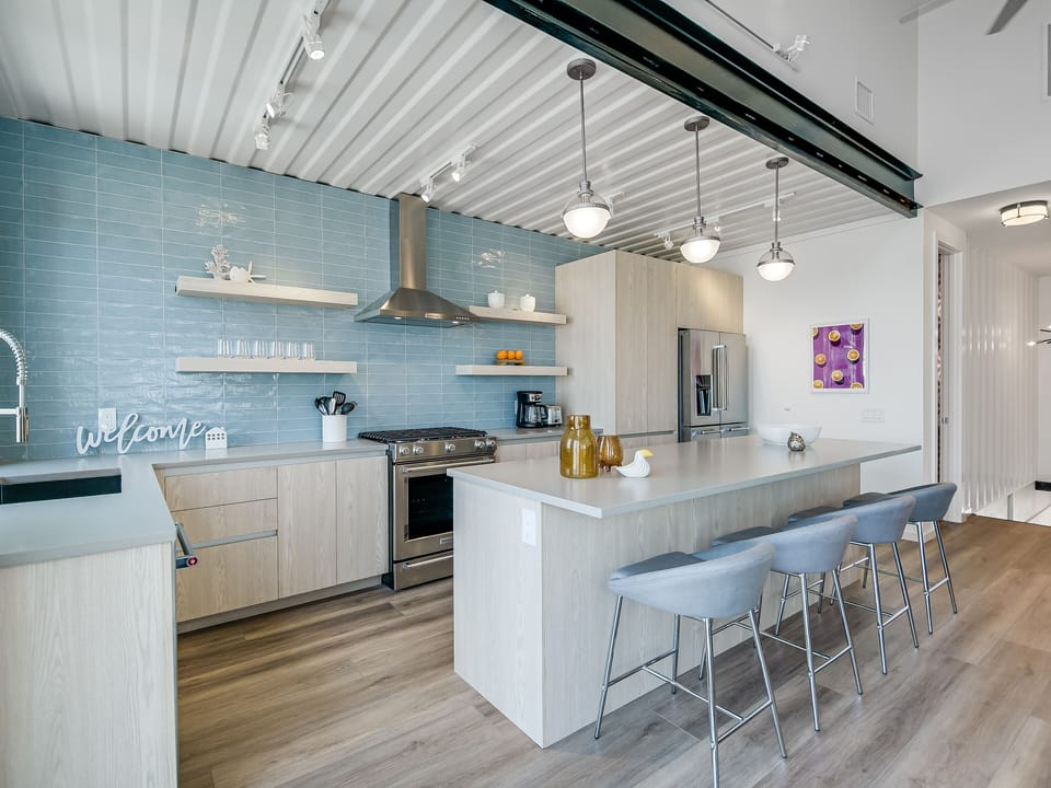 Your sleek kitchen features modern appliances, stunning blue tile backsplash, and spacious island seating for memorable meal prep.