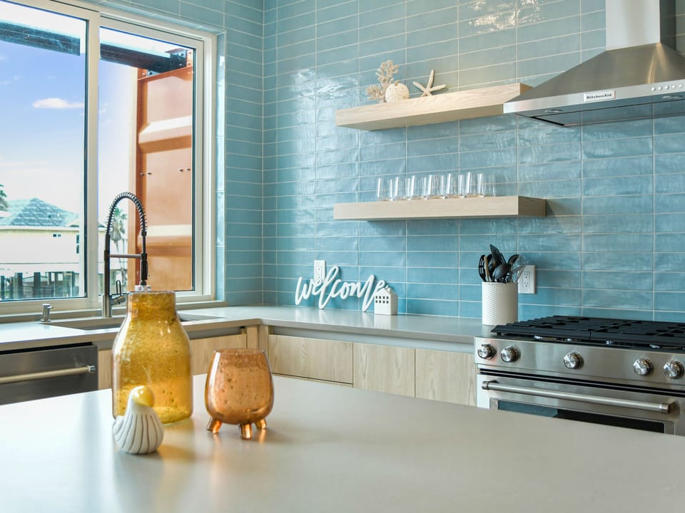 Your modern kitchen features stunning blue subway tile, professional appliances, and thoughtful coastal touches that make cooking a joy.