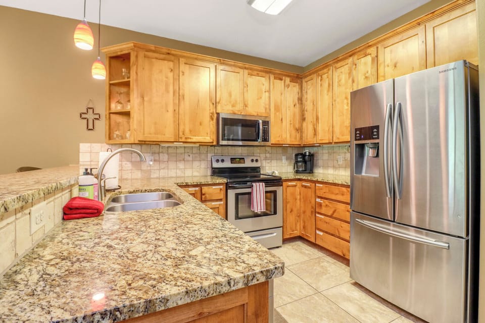 Prepare your favorite meals in this fully equipped kitchen, featuring granite countertops, modern stainless steel appliances, and warm wood cabinetry that creates a welcoming space for cooking together.
