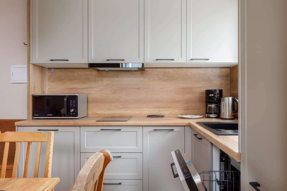 A modern kitchen with white cabinets, wooden countertops, and built-in appliances, offering a practical cooking space.
