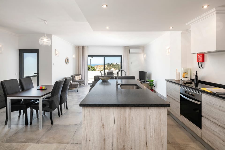 Modern open-plan living area with sleek kitchen, dining for six, and a lounge that opens onto a sea-view terrace. Perfect for relaxing or entertaining.