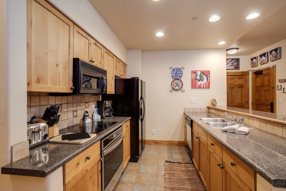 Your fully equipped kitchen awaits with granite counters, stainless appliances, and warm wood cabinets perfect for preparing meals together.