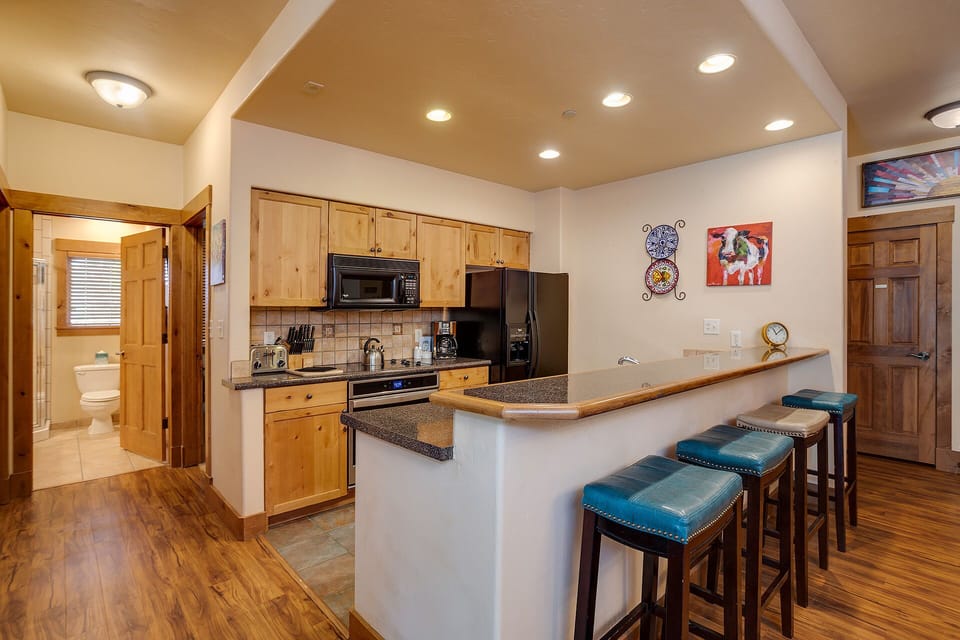 Your fully equipped kitchen features a spacious breakfast bar where you can enjoy morning coffee while planning your mountain adventures.