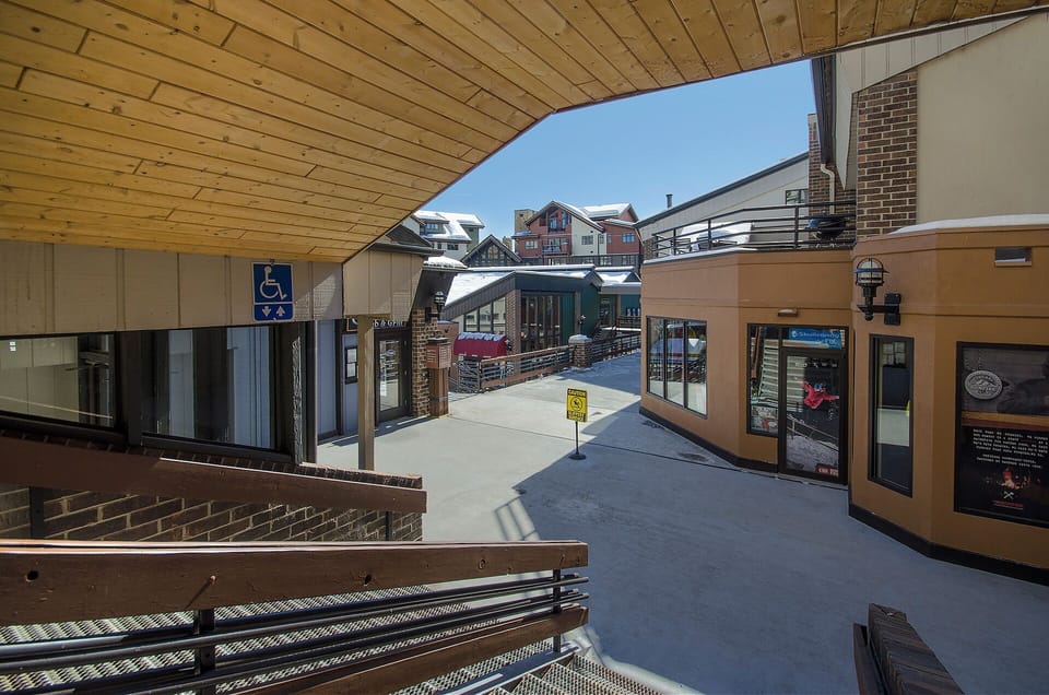 Modern shopping plaza with covered walkways leads to nearby mountain village amenities and services.