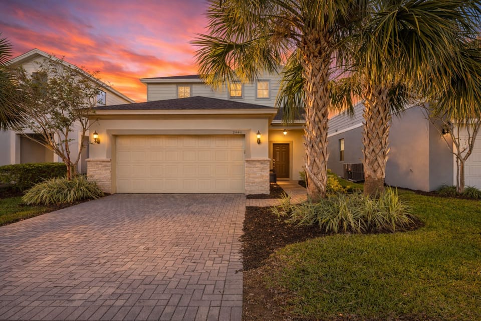 Tropical retreat with paver drive, 2-car garage, and sunset curb appeal