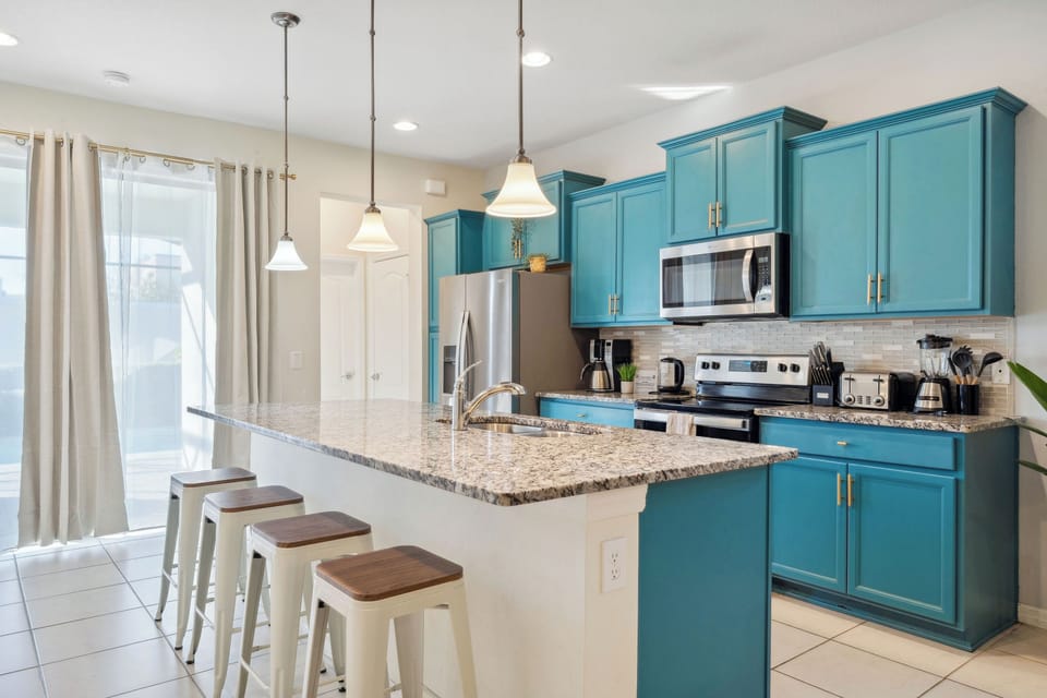 Bright kitchen w/ teal cabinets, granite island & stainless appliances