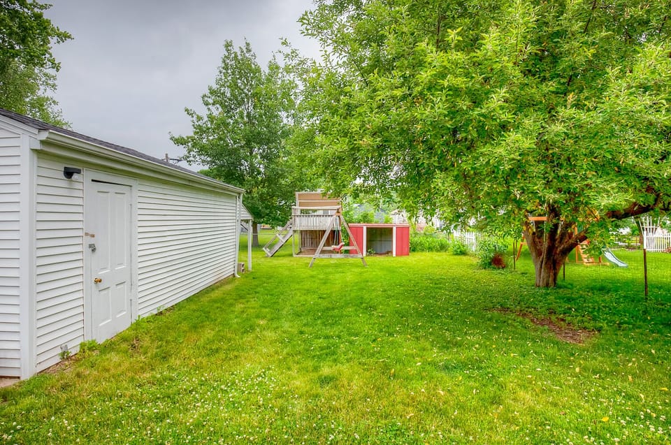 Partially fenced-in backyard with a tree for shade.