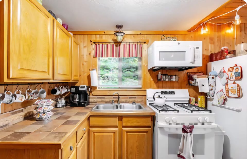 Kitchen is small but fully stocked with cookware, dinnerware, utensils, toaster.