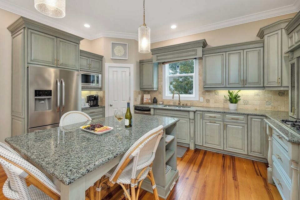 Sage green kitchen with granite island and bar stools