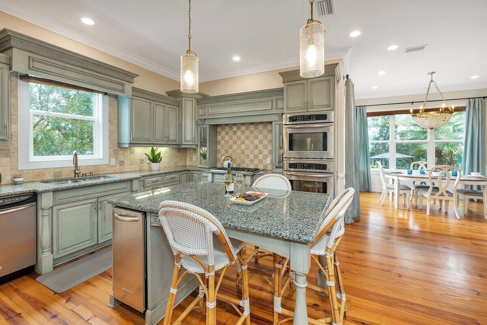 Sage kitchen with granite island, stainless appliances, dining view