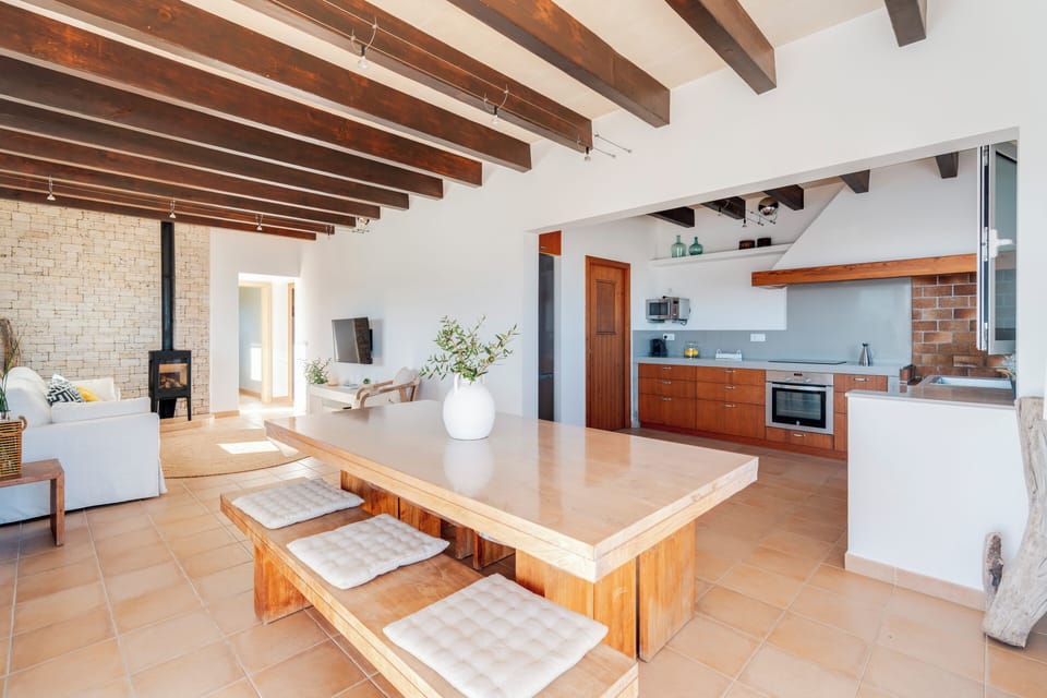 Vista general del salón-comedor con cocina completa abierta, tv, sofá y chimenea