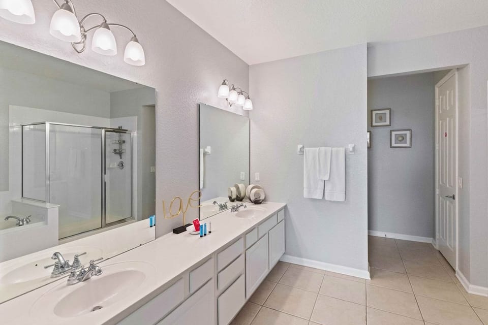 High-end Main bathroom of the condo in Orlando - Glamorous twin sink vanity with large wall mirrors and lamps - Fresh and cozy towels available including all bathroom amenities - neat and clean toilet seat