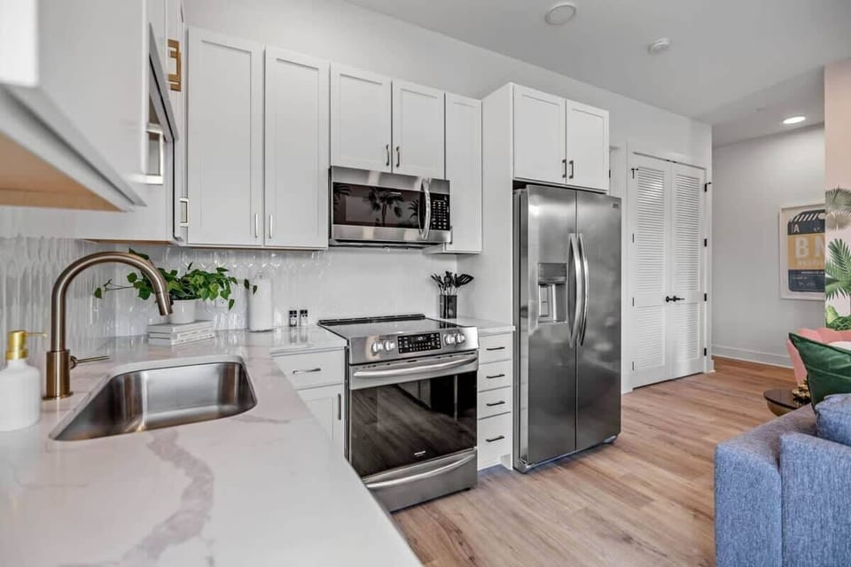 Experience an inviting fusion of modern elegance and rustic charm in this kitchen. Sleek wood floors seamlessly harmonize with a splash of blue from a plush couch, creating a perfect blend of comfort and style that defines a contemporary yet cozy ambiance.