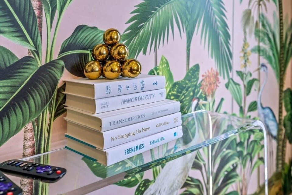 Indulge in a Slice of Paradise as you step into your personal oasis within our stunning living room. Boasting lush tropical wallpaper and a chic glass shelf, this space offers an exquisite blend of relaxation and sophistication.