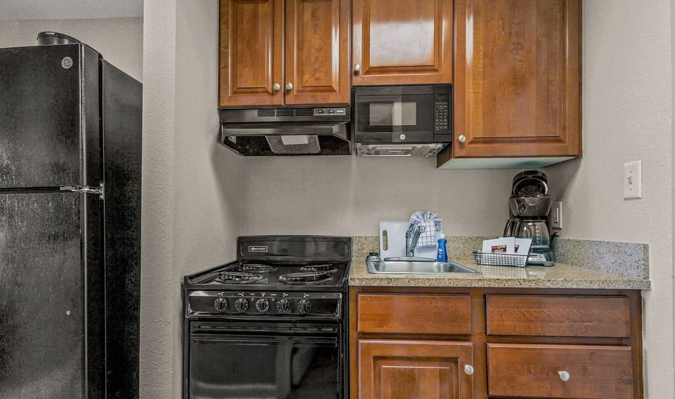 Fully equipped kitchenette with stove, fridge, microwave, and wood cabinets