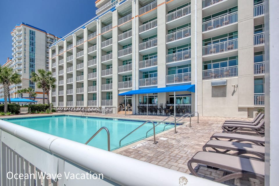Outdoor pool with lounge chairs and balconies, ideal for coastal relaxation