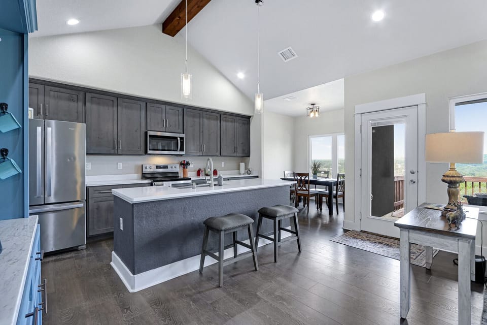 This is a view showing the kitchen of the home.  You can also see the dining room table in the distance as well as the door that leads to the large back deck.
