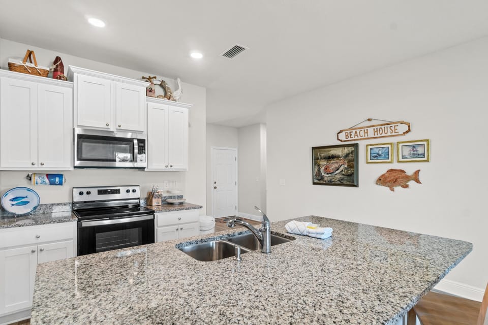Your fully-equipped kitchen features granite counters and coastal charm, perfect for preparing meals with ocean-inspired décor.