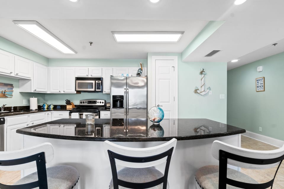 Your fully-equipped kitchen features granite countertops, stainless appliances, and charming coastal decor perfect for preparing meals together.