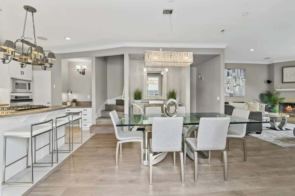 Elegant open-concept dining space with plenty of seating—gather around the sleek glass table or enjoy a casual bite at the stylish breakfast bar. Perfect for group meals and entertaining!