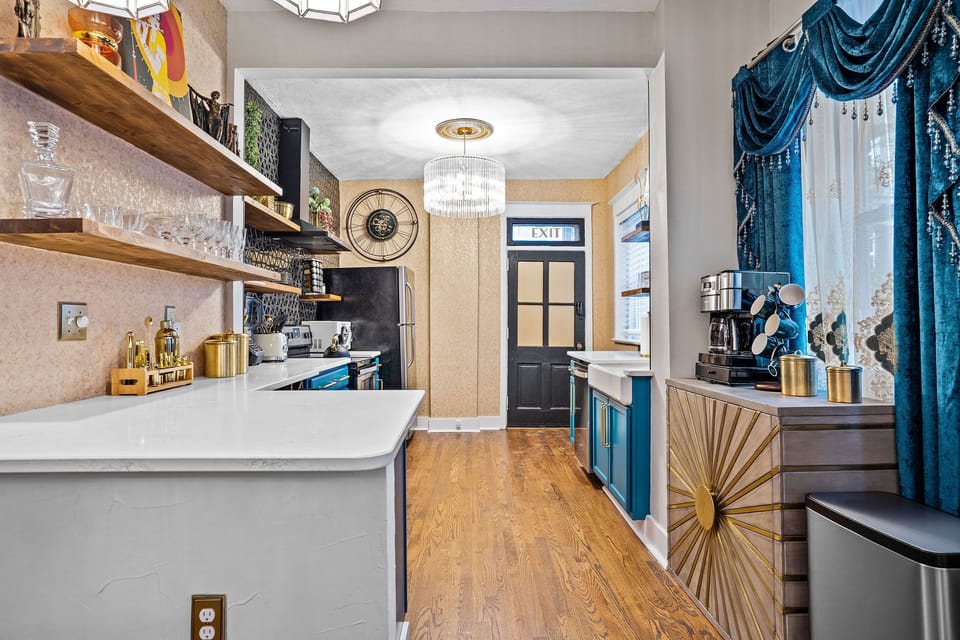 Cook in style in The Gatsby’s fully equipped lower-level kitchen, featuring bold blue cabinetry, open shelving, quartz counters, and modern appliances—perfect for extended stays in Midtown Kansas City.