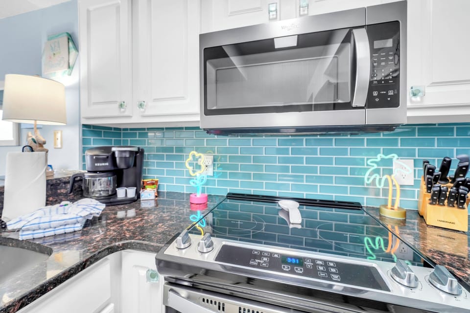 Cook your favorite meals in this fully-equipped kitchen featuring modern appliances and beautiful turquoise tile backsplash.