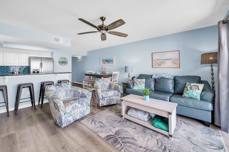 Relax in your bright, coastal-themed living space with comfortable seating and a modern kitchen perfect for vacation cooking.
