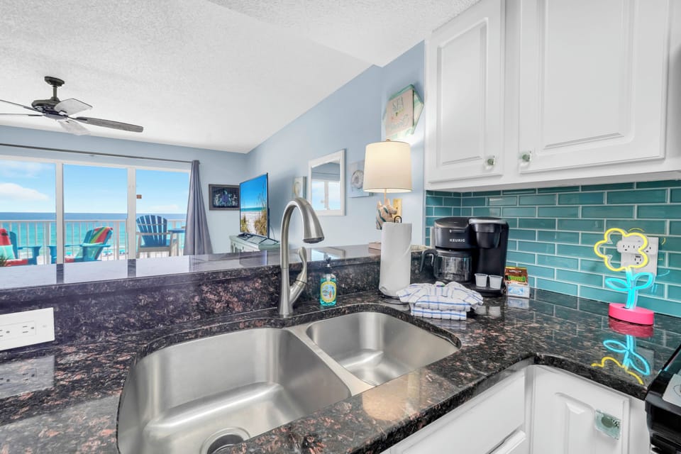Prepare meals with stunning ocean views from your granite kitchen. Modern appliances and cheerful teal backsplash create the perfect beachside cooking space.
