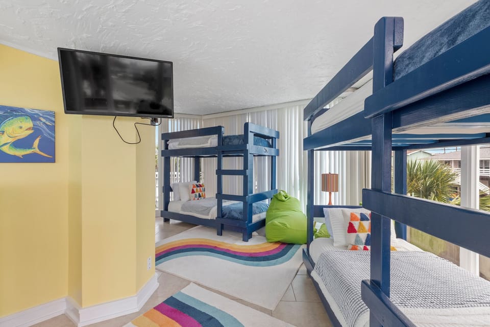 Your kids will love this colorful bunk room with multiple beds, fun rainbow rug, and their own TV for movie nights.