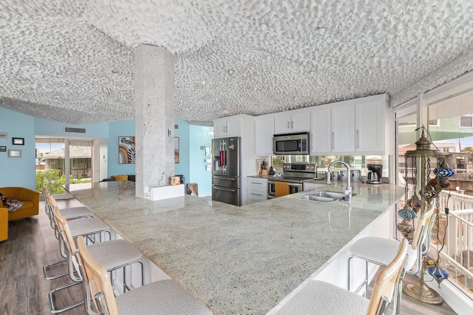 Step into your modern kitchen featuring granite countertops and stainless steel appliances, perfect for preparing meals while enjoying ocean breezes.