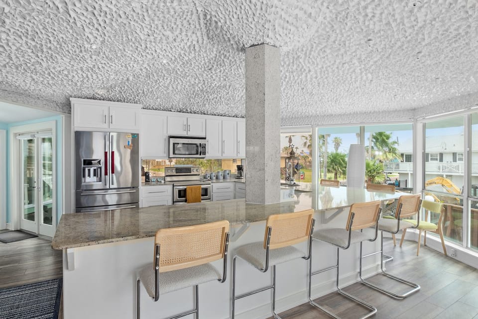 Your modern kitchen island becomes a culinary stage with sleek appliances and stunning views through floor-to-ceiling windows.
