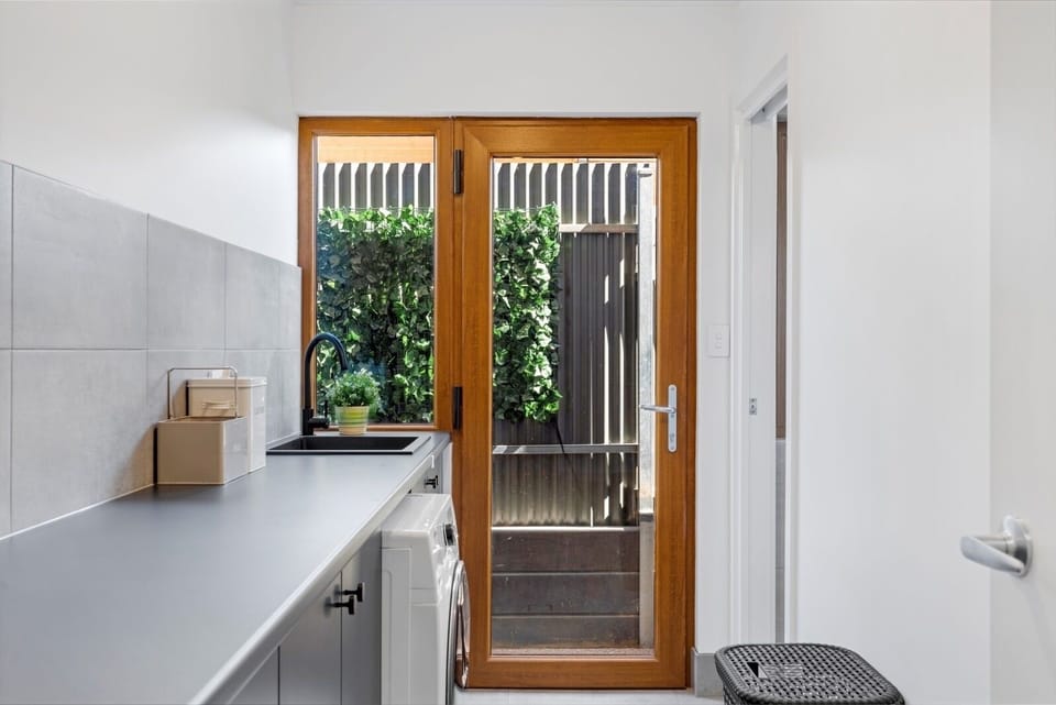 Spacious laundry with washing machine, iron and small ironing board 