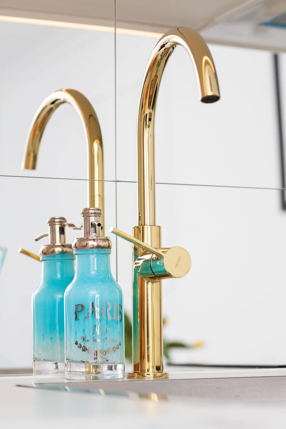 A close-up of a golden faucet and stylish soap dispensers, adding a touch of elegance to the bathroom.
