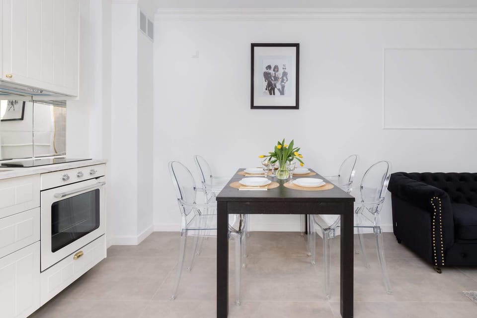 A dining area with a sleek black table, transparent chairs, and vibrant decor, creating a contemporary vibe.

