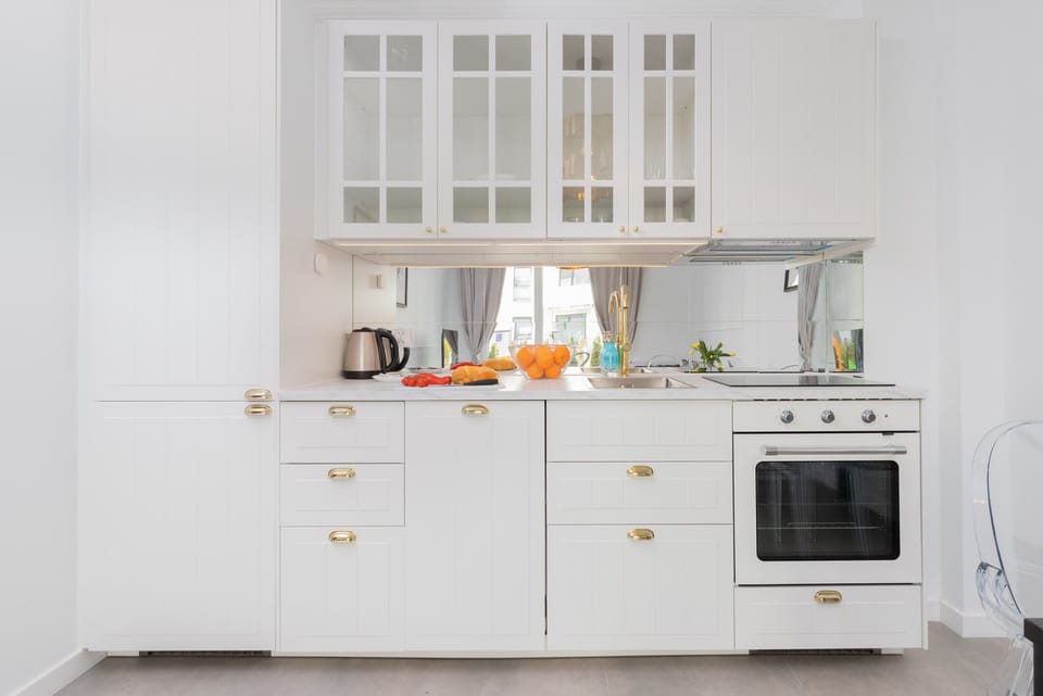 A modern kitchen with white cabinets, golden handles, and a clean, bright design, blending functionality and style.
