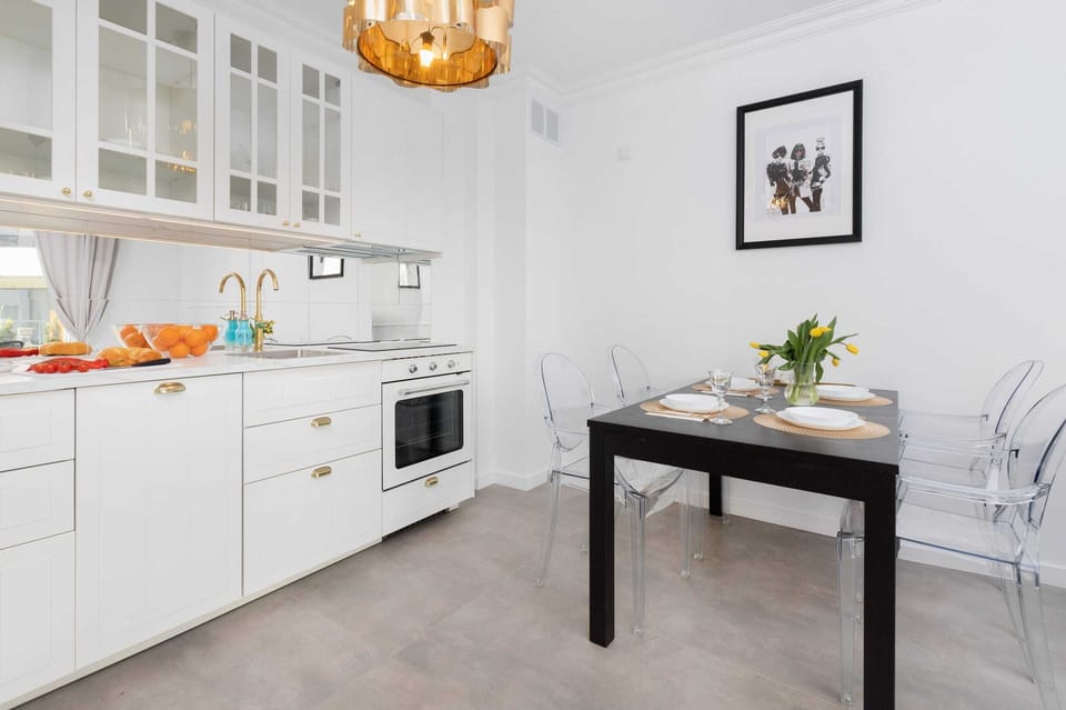 A modern kitchen with white cabinetry, a dining table, and chic decor, blending functionality with aesthetics.

