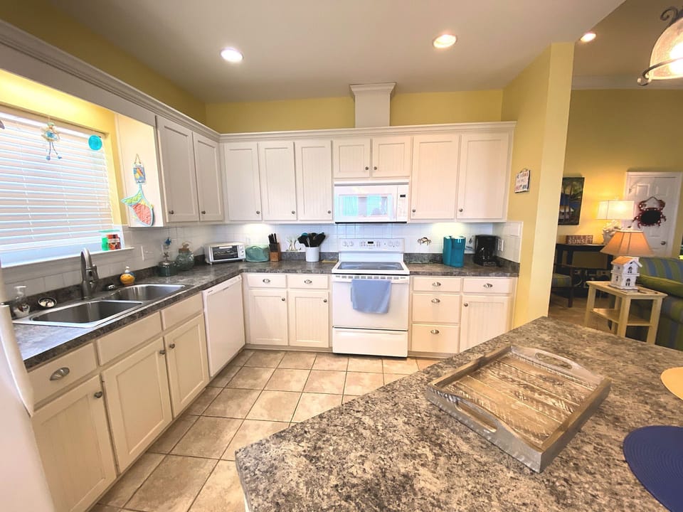 Your fully-equipped kitchen awaits with granite counters, white cabinets, and all appliances needed for preparing memorable meals during your stay.
