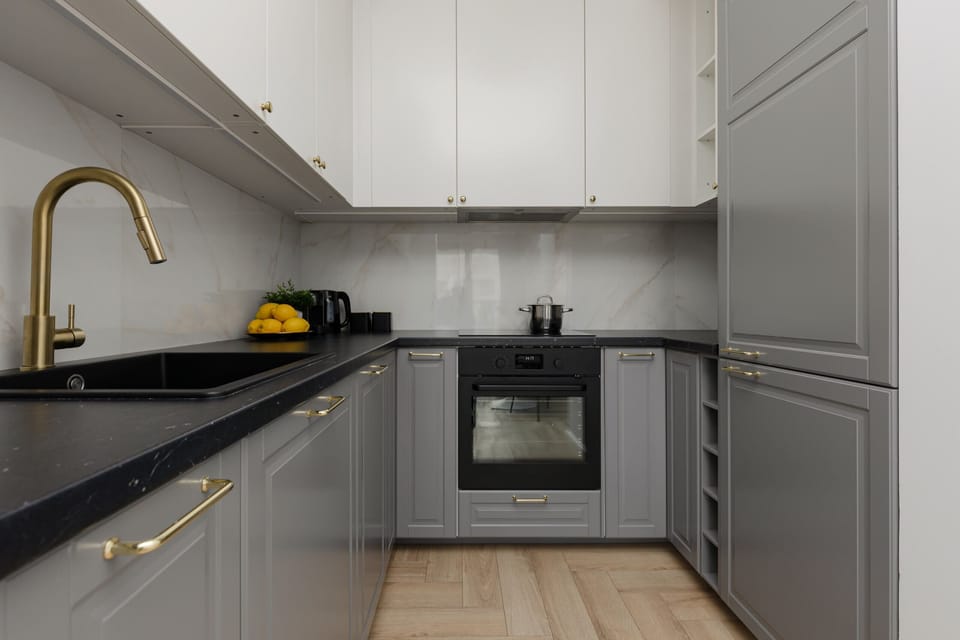 A sleek kitchen with gray cabinetry, white countertops, and modern appliances, blending functionality with style.
