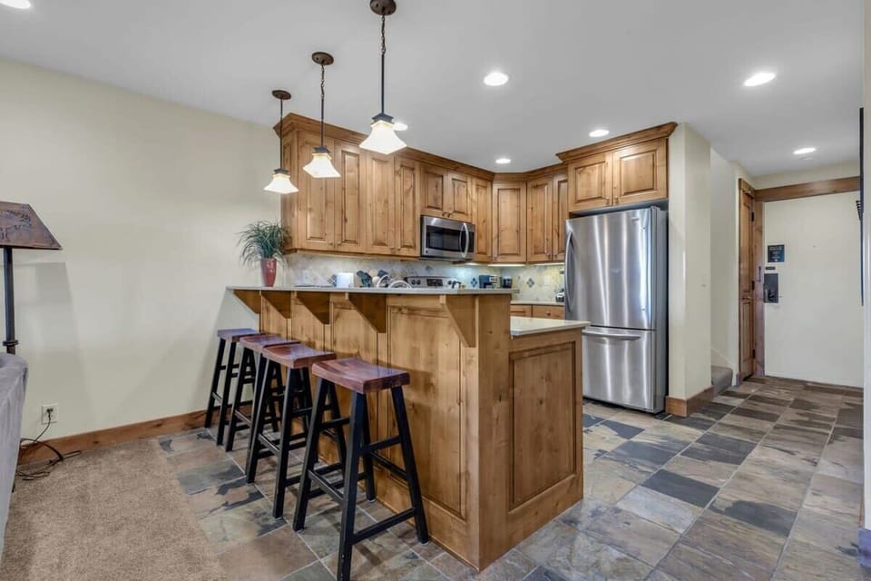 The fully equipped kitchen features stainless steel appliances, classic wood cabinets, and seating for four at the kitchen bar.