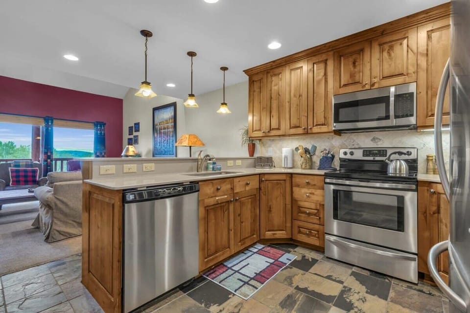 The fully equipped kitchen features stainless steel appliances, classic wood cabinets, and seating for four at the kitchen bar.