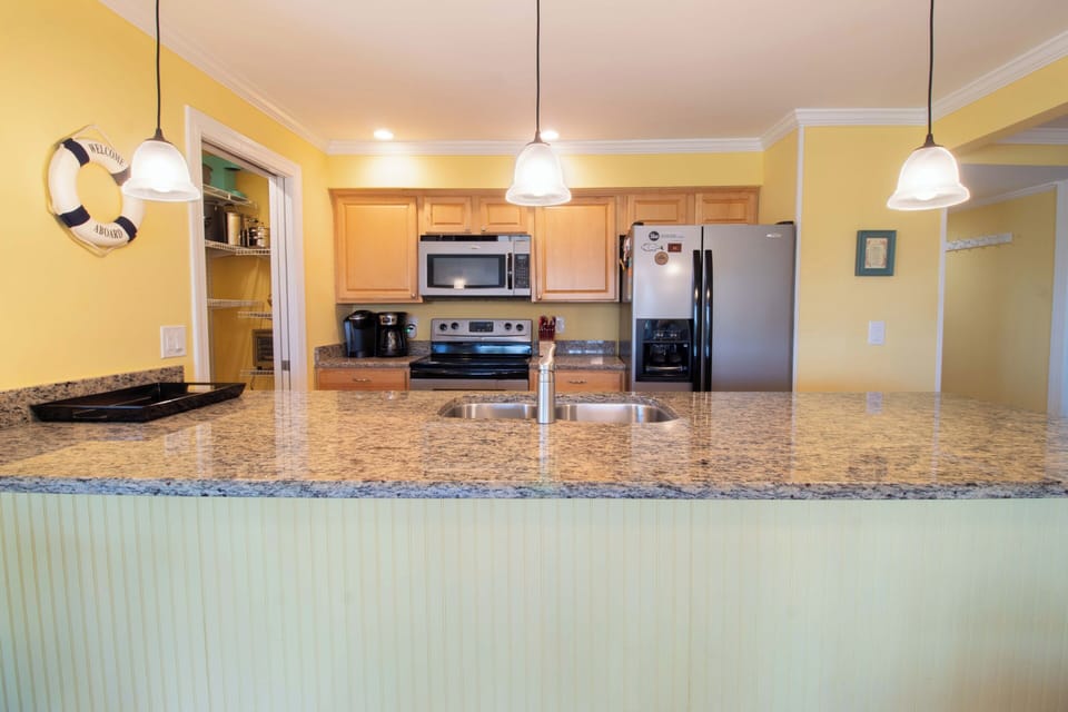 Step into your fully equipped kitchen with granite countertops, modern appliances, and bright pendant lighting—perfect for preparing family meals or morning coffee during your stay.