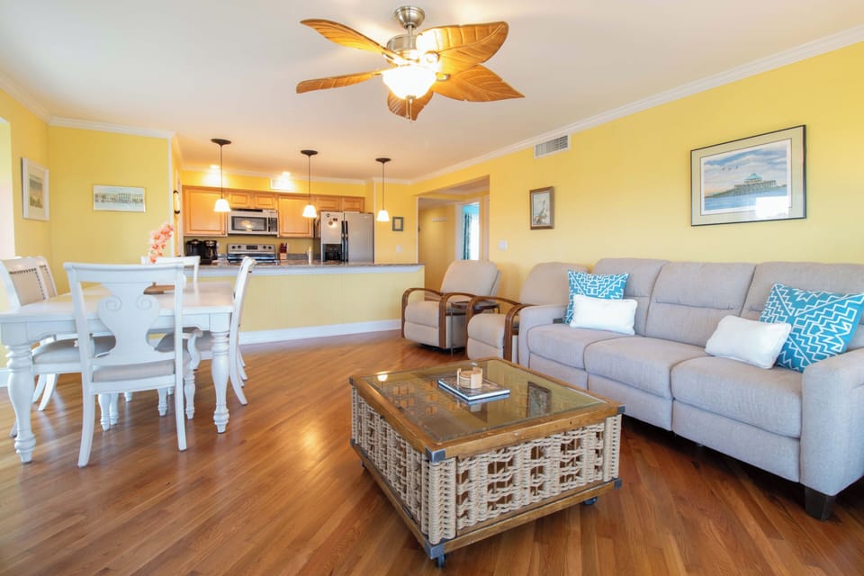 Step into this bright, open living space where cheerful yellow walls and coastal accents create a welcoming atmosphere. Relax on the comfy sofa, gather around the dining table, and feel right at home.
