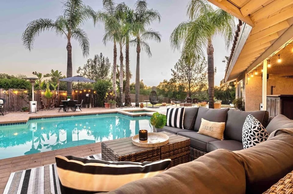 Your private resort right in your backyard, featuring calm pool waters, plush outdoor seating, and the gentle glow of warm string lights. Surrounded by palm trees, it’s the perfect escape for relaxation, making your stay extra special.